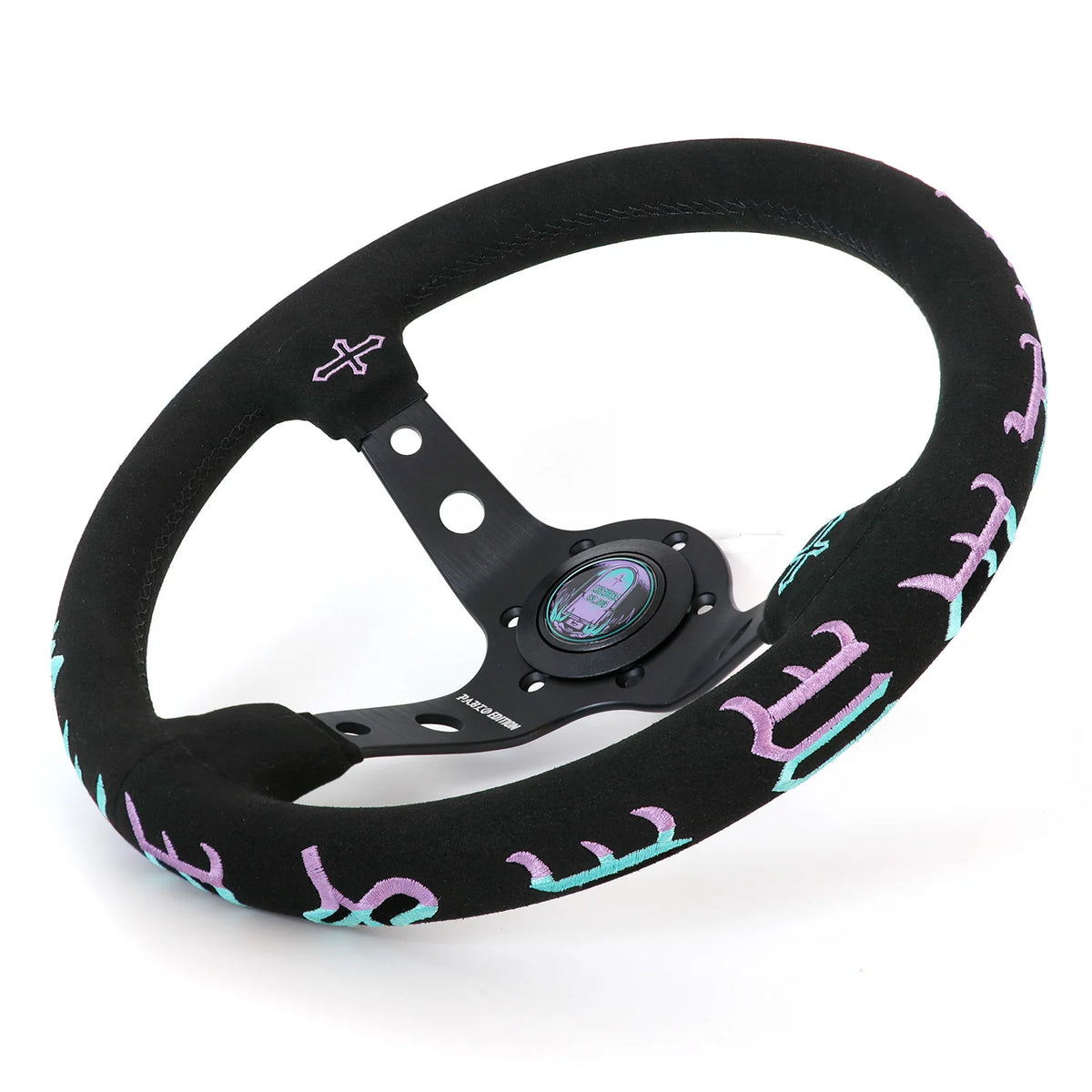A black racing steering wheel with a textured suede-like rim and purple gothic-style lettering, shown on a white background.