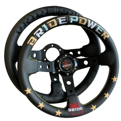 A black racing-style steering wheel with gold star accents and yellow stitching, featuring 'BRIDE POWER' branding in gold, blue, and white lettering on the top rim.