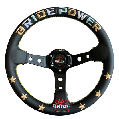 A black leather-wrapped car steering wheel with gold star accents, yellow stitching, and 'BRIDE POWER' lettering in gold, blue, and white on the rim. The center cap features the Bride logo.