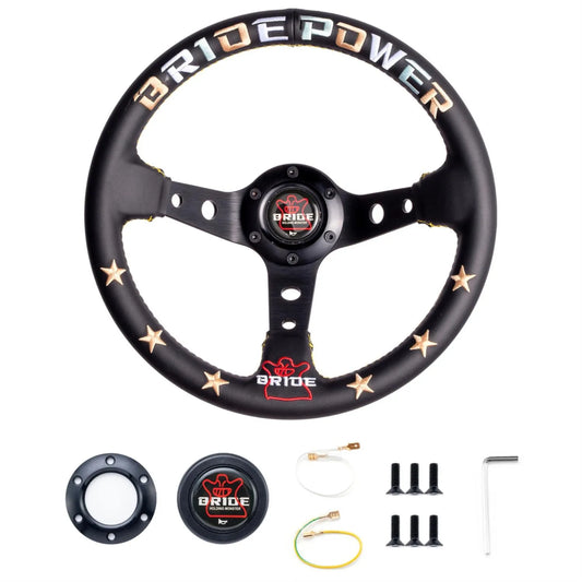 A black three-spoke car steering wheel cover with gold stars and 'BRIDE POWER' branding, shown with mounting hardware and a matching center cap on a white background.