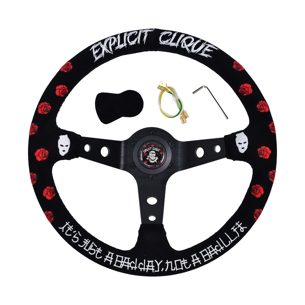 A black custom steering wheel with red rose patterns, white gothic text, and white mask graphics, shown with its mounting hardware on a white background.