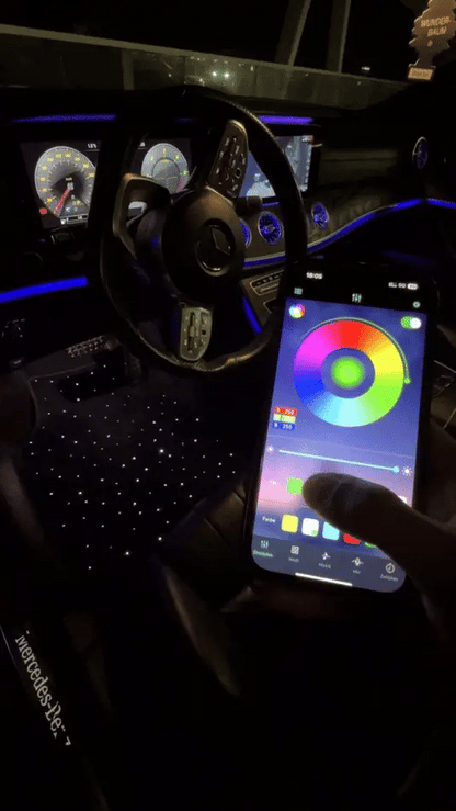 Car interior with smartphone displaying a color wheel app controlling starlight floor mats
