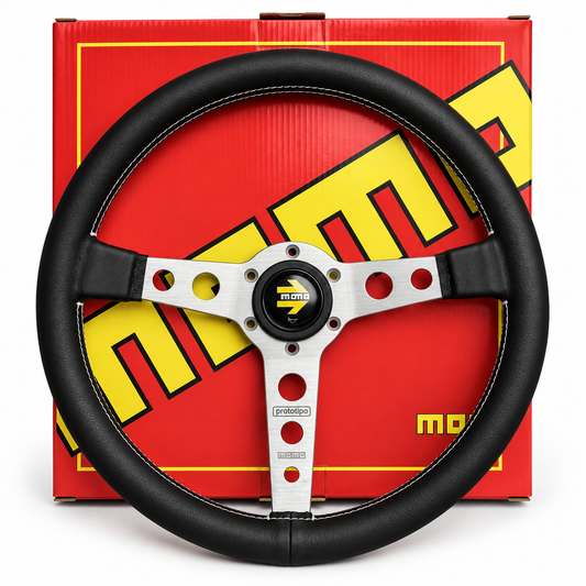 A black leather-wrapped racing steering wheel with a silver three-spoke center and a black-and-yellow Momo logo, shown in front of its red and yellow branded retail box.