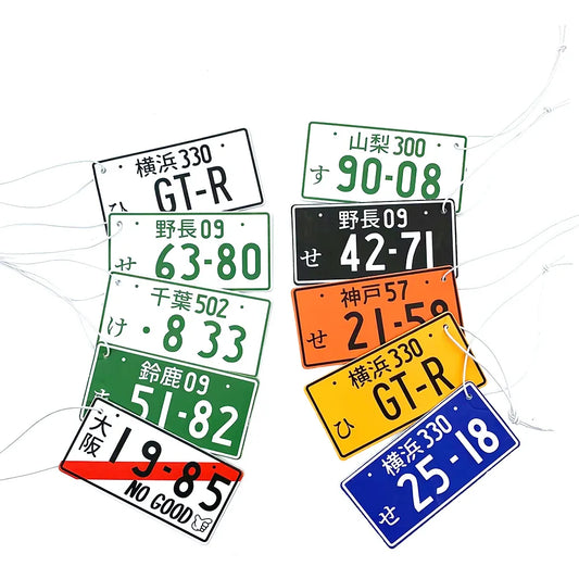 A collection of Japanese licence plate air fresheners with various numbers and colors displayed.