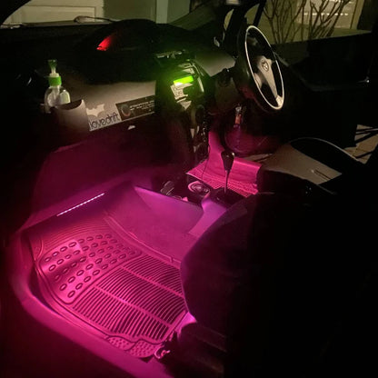 Car interior with pink floor mats and a bottle of water on the dashboard.