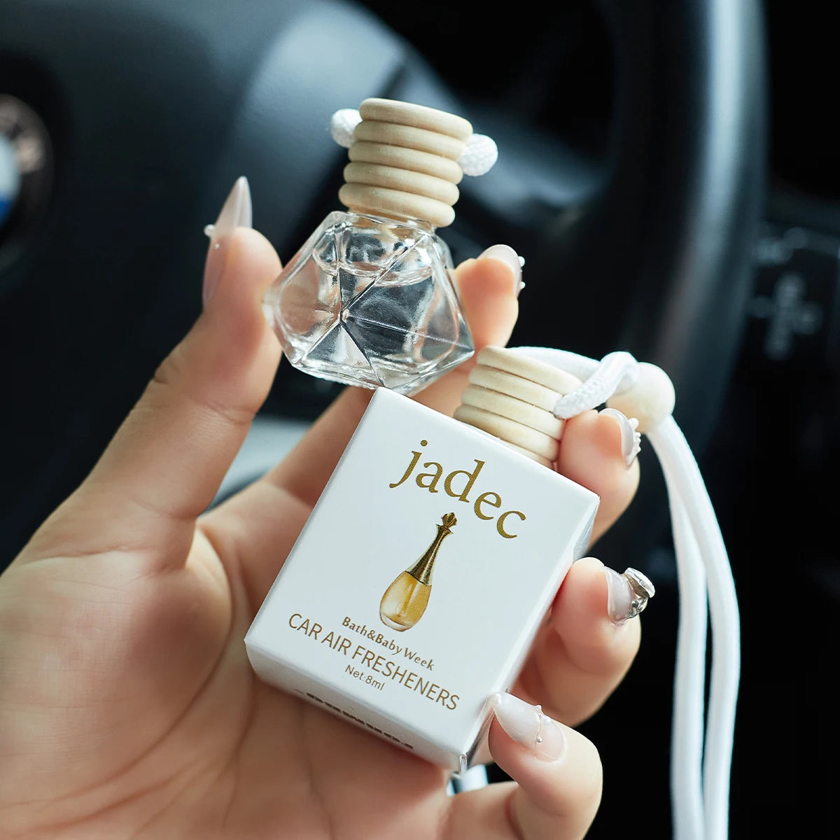 Car air freshener with 'jadec' branding held in a hand against a blurred car interior background.