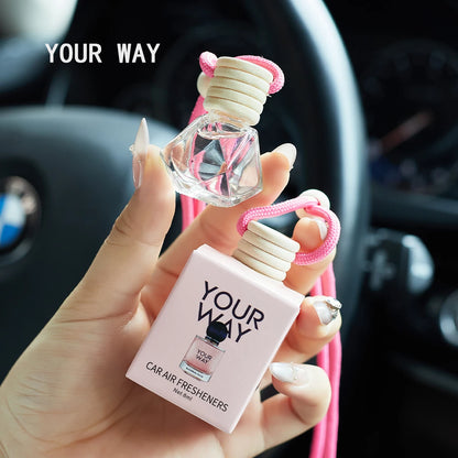 Car air freshener with 'Your Way' branding held by a hand inside a car.